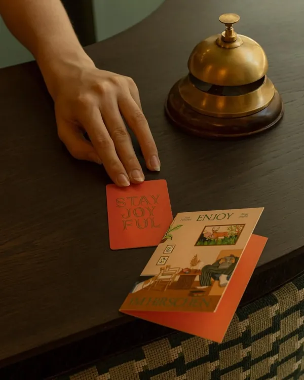 A hand at a hotel reception bell with a room key card