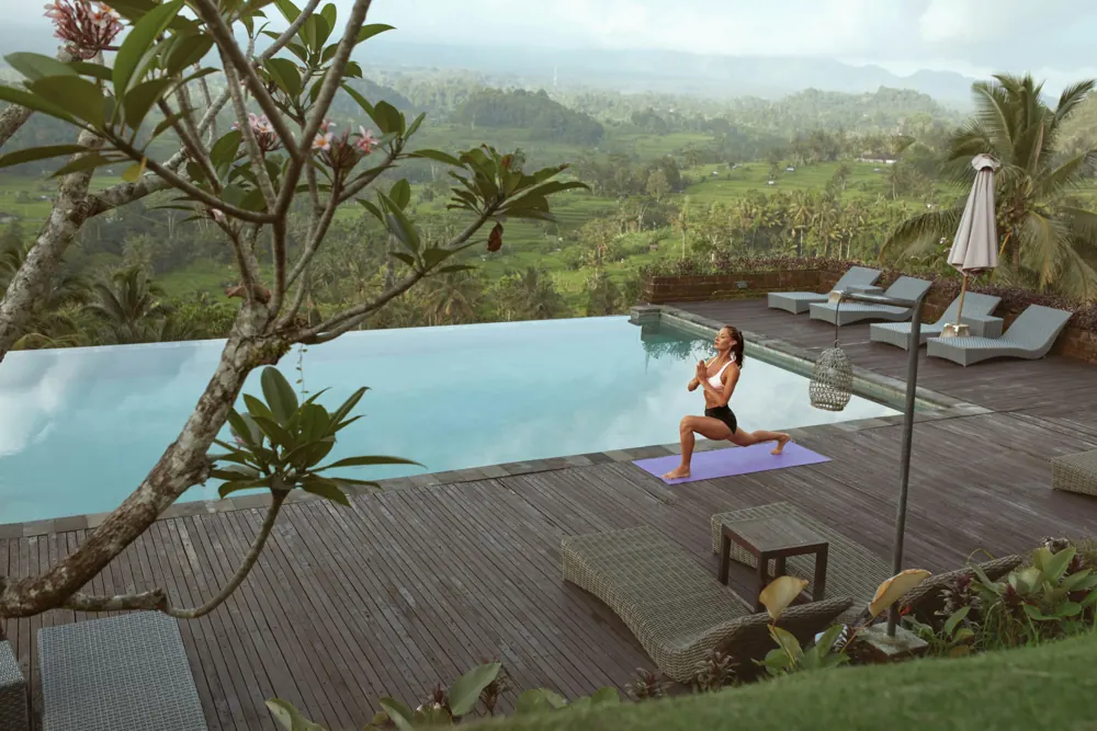 A guest doing yoga on a pool deck above rice terraces